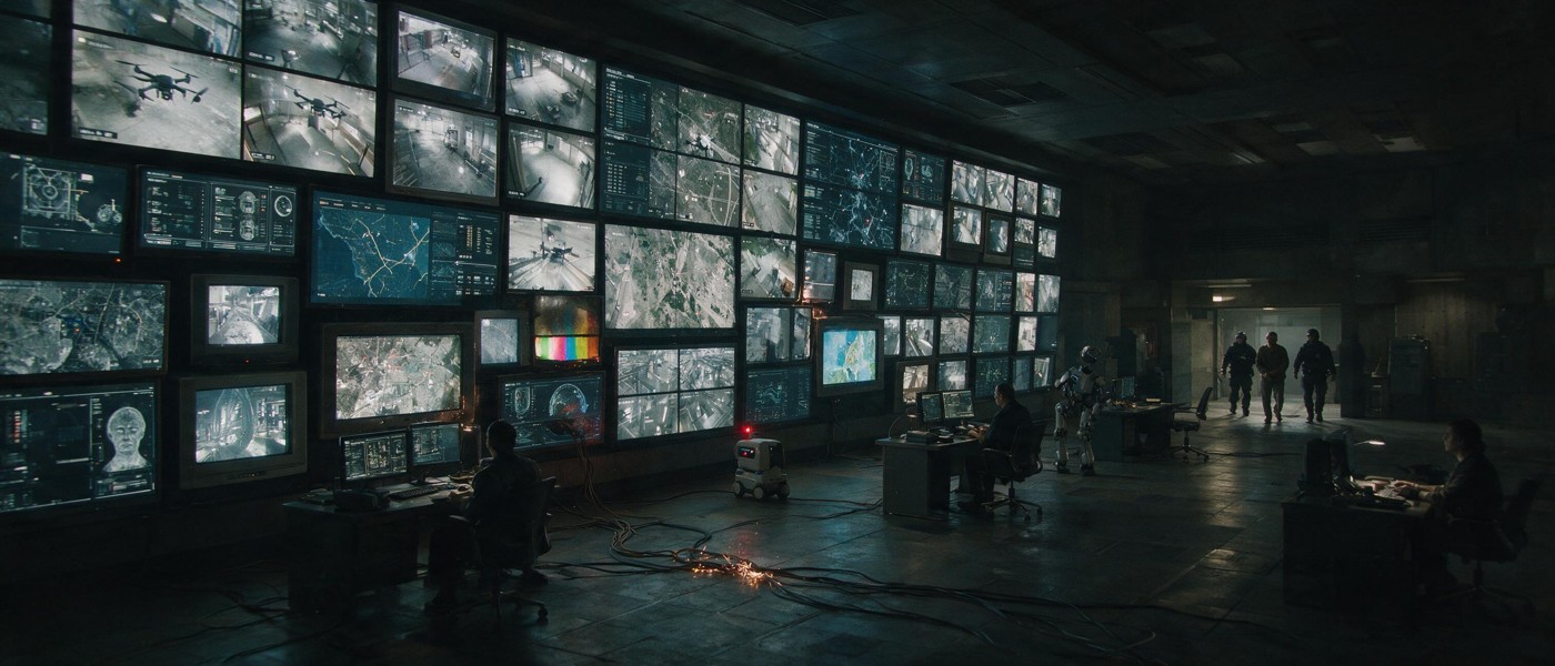 THE CONTROL ROOM: A wall of images. A city under observation.